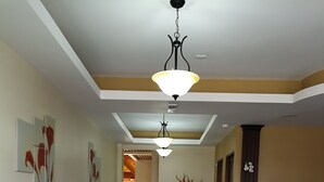 A lobby with a reception desk, a seating area with sofas, a chandelier, and artwork on the walls. - Vivens Bed & Breakfast Sarchi (Sarchí Sur)