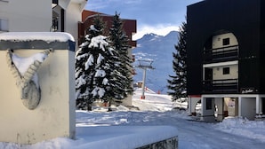 Calle cubierta de nieve con edificios, incluyendo un hotel llamado "Le Sarbier" con una pancarta.