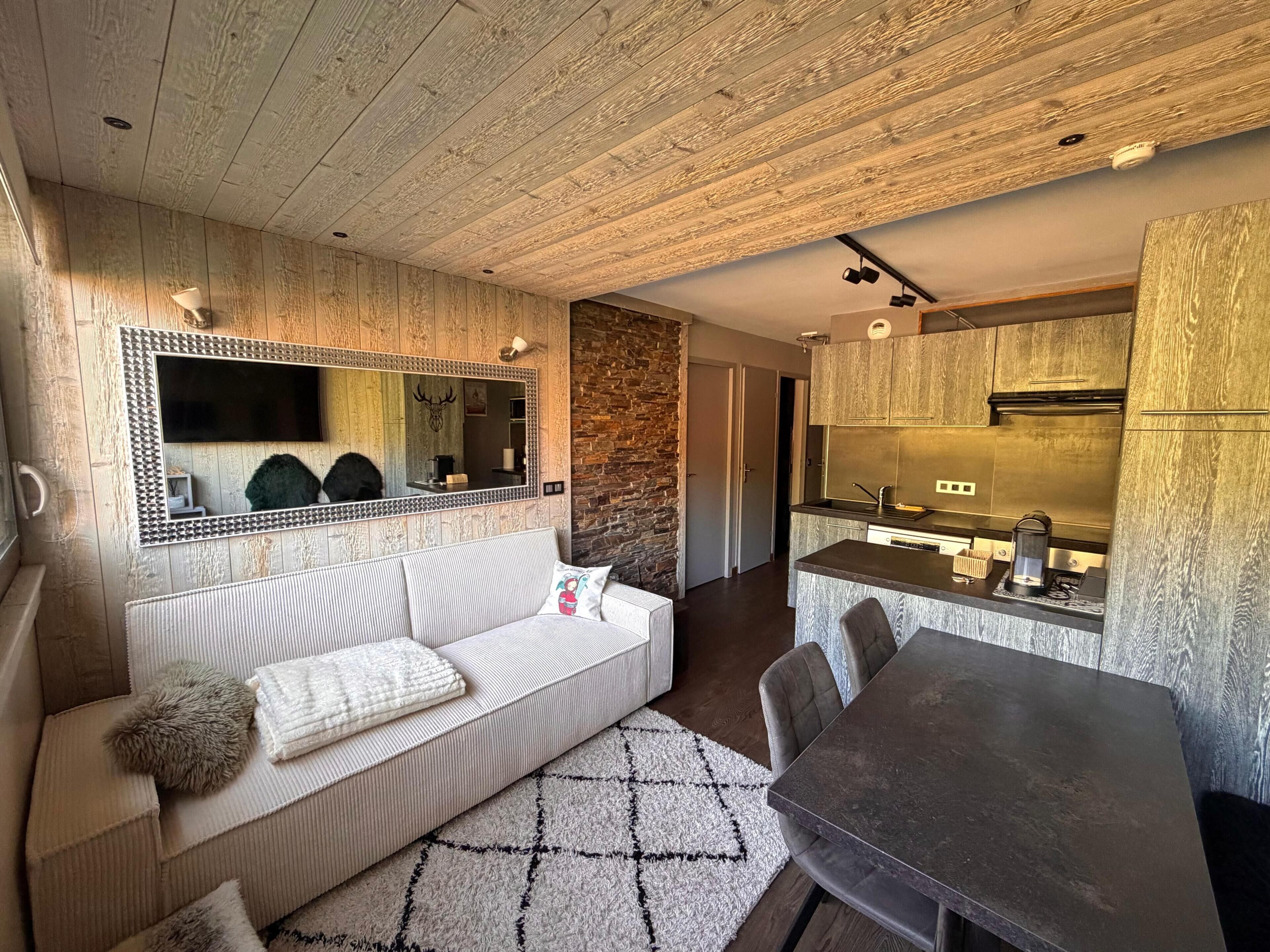 A modern interior with a sofa, a dining table, a kitchen area, and a large mirror.