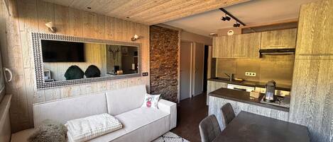A modern interior with a sofa, a dining table, a kitchen area, and a large mirror.