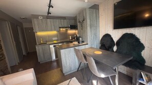 A modern kitchen with grey cabinetry, a built-in island, and a flat-screen TV mounted on the wall. - Rare in Les Menuires, beautifully renovated 3-room apartment with ski-in ski-out (LES MENUIRES)