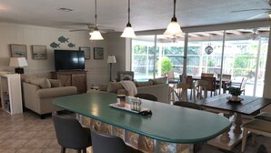 A spacious living area with a large island, bar stools, a dining table, and a TV. - Single open-concept home one block from the ocean with heated pool and lanai  (West Palm Beach)