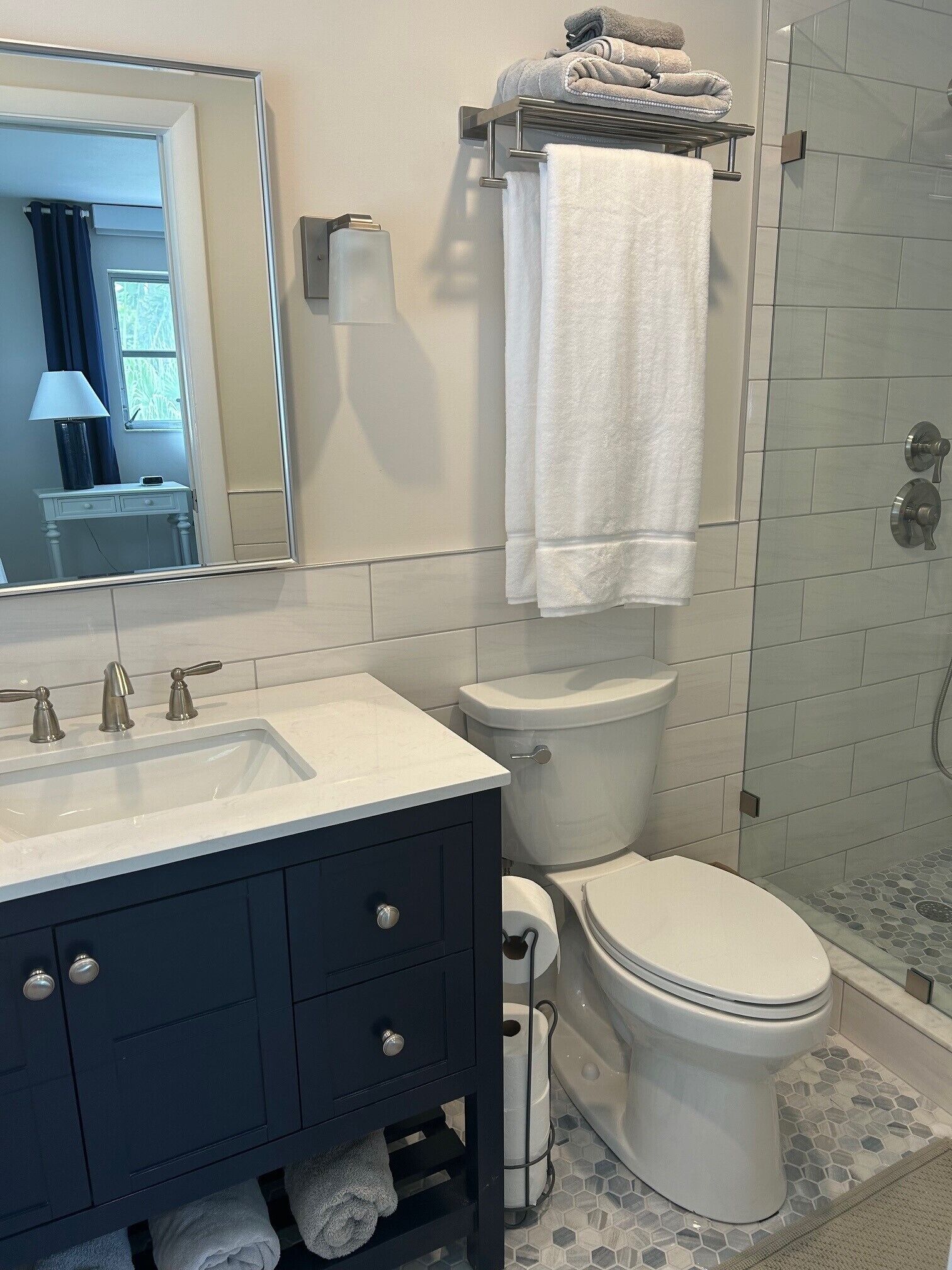 A bathroom with a white sink, dark cabinets, a toilet, and a shower area.