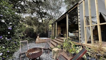 A rustic outdoor seating area with a fire pit, lounge chairs, and a wooden deck.