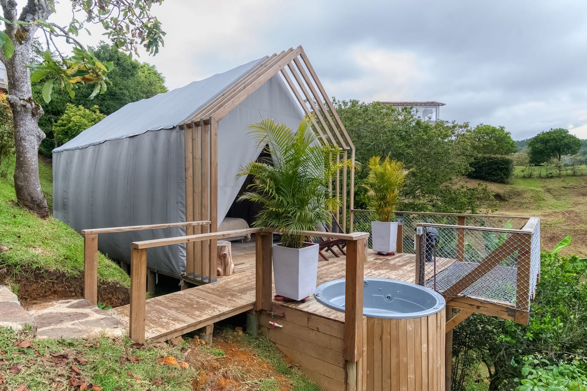 A wooden deck with a hot tub, a covered area, and a fenced deck area.
