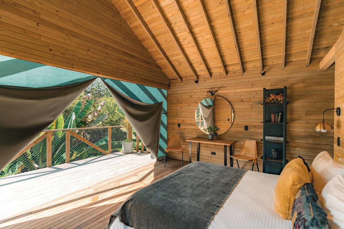 A wooden cabin with a bed, a small table, a chair, and a bookshelf.