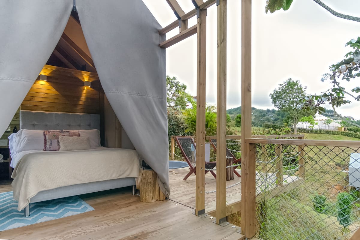 A bedroom with a canopy bed, a view of the outdoors, and a wooden deck.