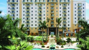 Un hôtel à plusieurs étages doté d’une cour intérieure où se trouvent une piscine, des palmiers et une fontaine.