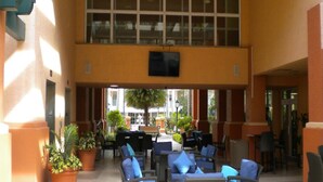 Un espace extérieur abrité, aménagé avec plusieurs chaises et tables, et entouré de plantes en pot.