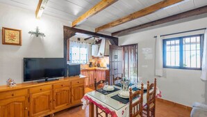Une cuisine chaleureuse avec des meubles en bois, un téléviseur et un coin repas avec une table mise pour deux personnes.