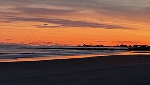Ranta auringonlaskun aikaan, kirkas taivas ja tyyni meri.