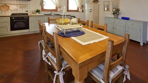 A dining area with a wooden table and chairs, a kitchen in the background, and a calendar on the wall. - Four leaf clover - Salvia (4 + 2) (Gambassi Terme)