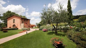 A rustic house with a paved pathway leading to the entrance, surrounded by well-maintained lawns and flowering plants. - Four leaf clover - Salvia (4 + 2) (Gambassi Terme)
