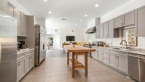 Een moderne keuken met roestvrijstalen apparatuur, een houten eettafel en lichte kasten.