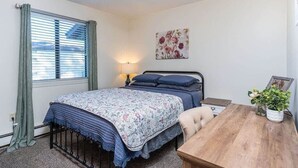 Une chambre à coucher avec un lit, une table de chevet, une lampe et un tableau accroché au mur.