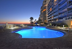 Relax by the pool overlooking the ocean with lounge chairs and a scenic view.