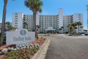 En hotellentrén med en skylt som visar texten ”Sterling Sands” och en modern byggnad i bakgrunden.