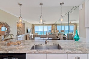 Enjoy ocean views from the kitchen's large window, which is part of a spacious open-plan living area with a dining space and seating.