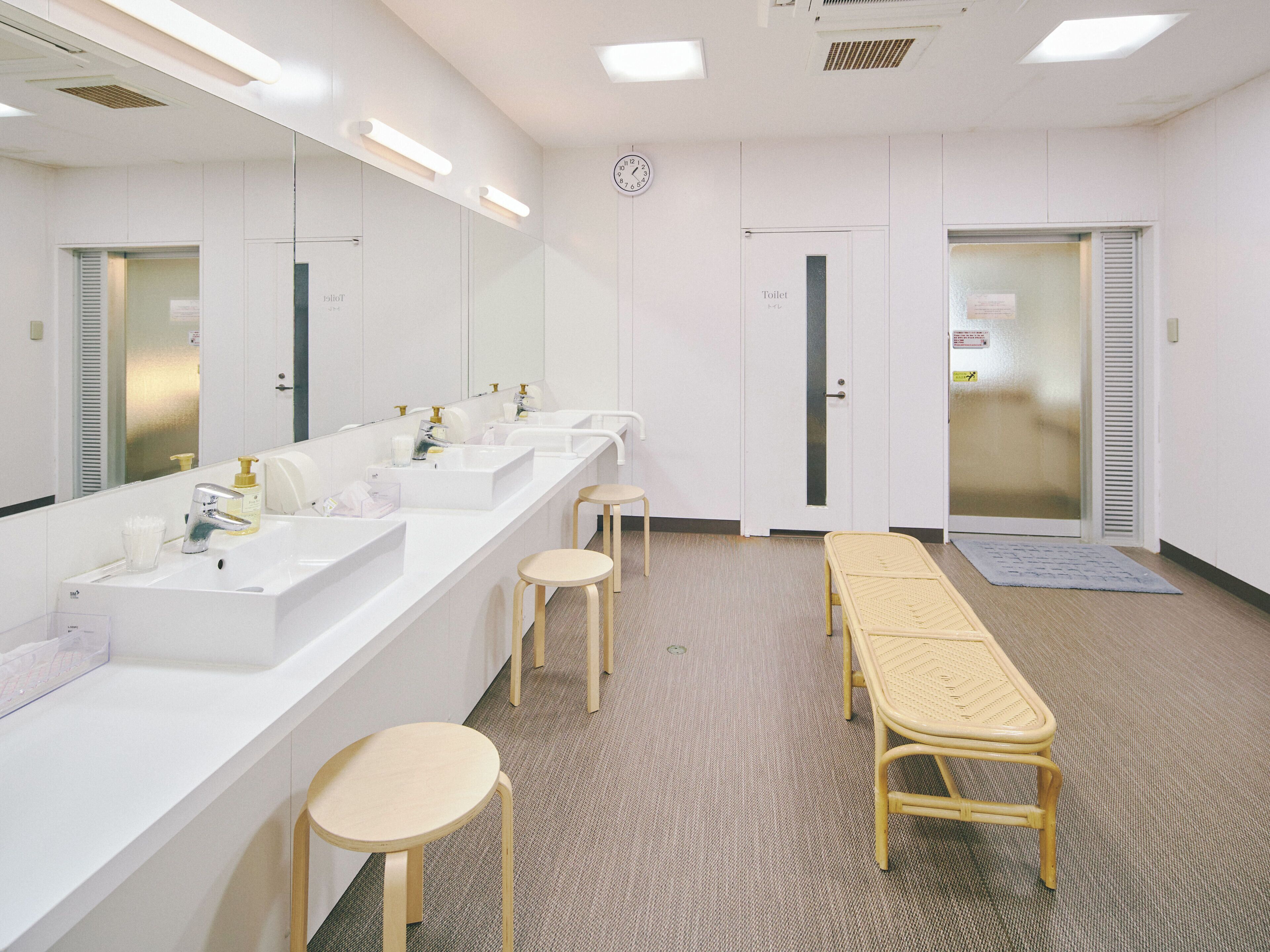 A clean, modern bathroom with two sinks, a mirror, and a bench.