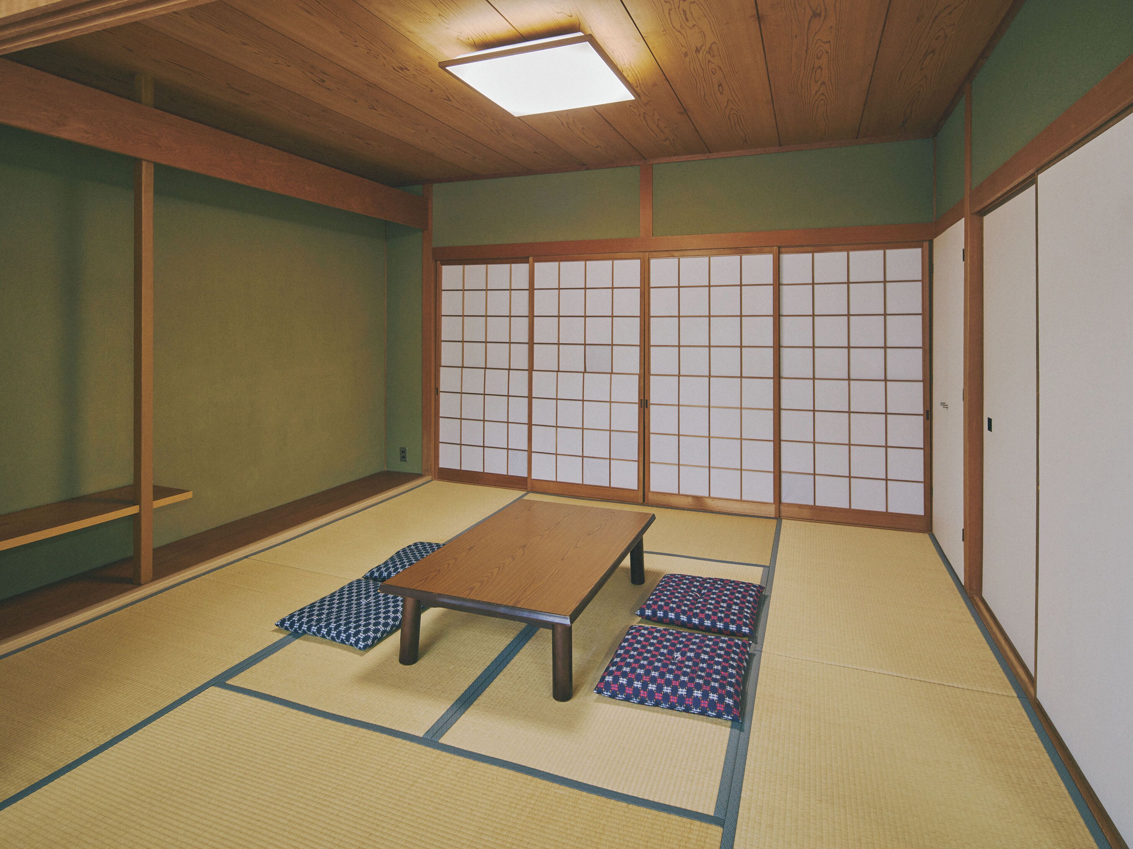 Una habitación con esteras de tatami, una mesa de madera baja, cojines y puertas correderas shoji.