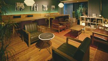 A modern lounge area with leather seating, a round table, and artwork on the walls.