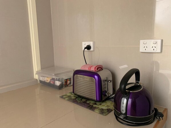 A kitchenette with a toaster, kettle, and storage container.