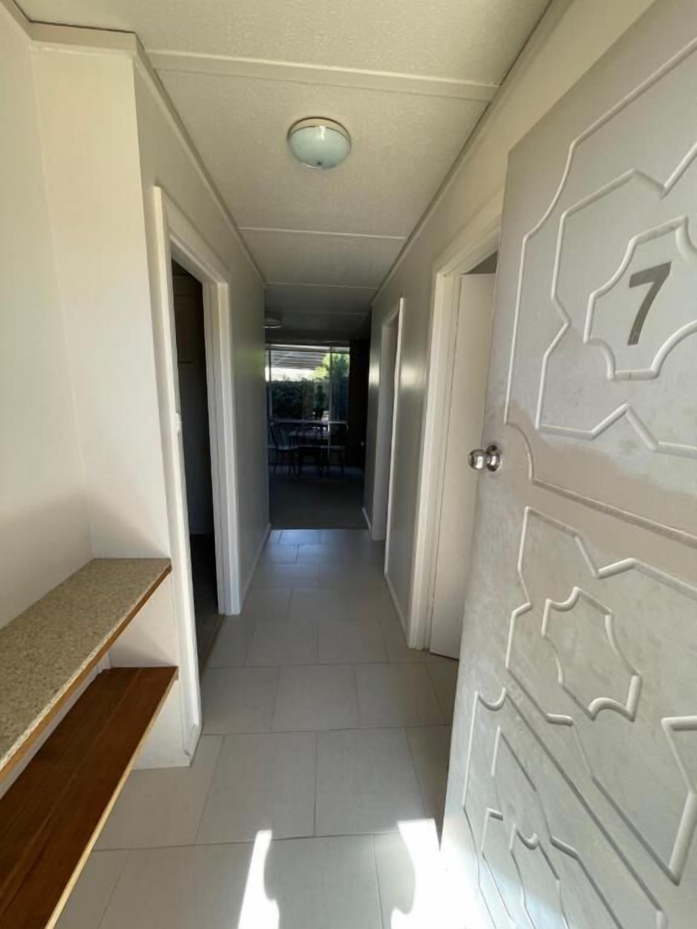 Un pasillo con una puerta marcada con el número 7, que da a otra habitación.