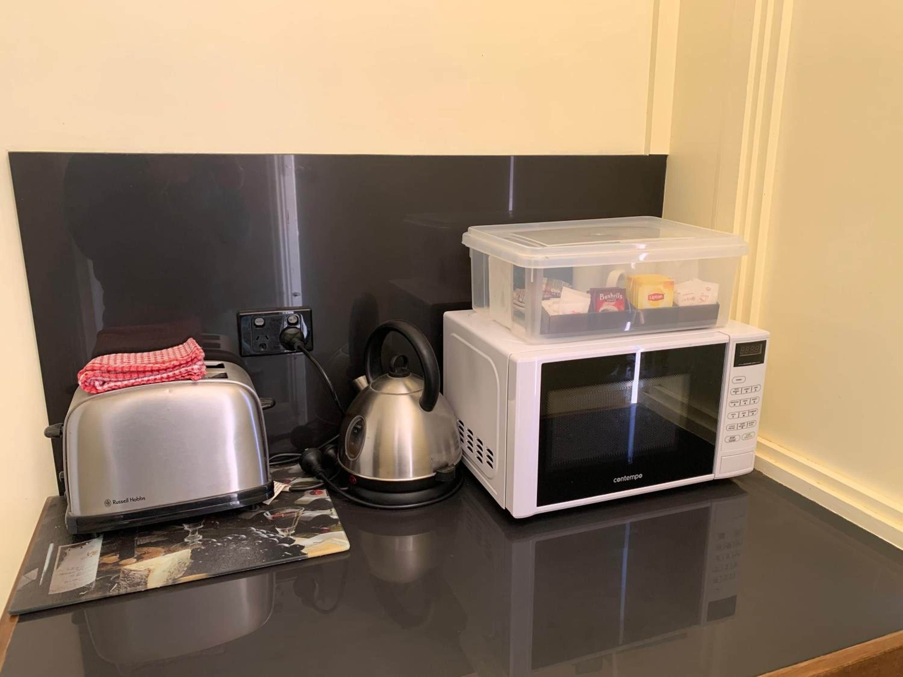 Una encimera de cocina con un tostador, un hervidor y un microondas.