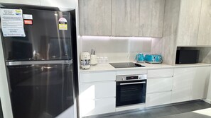 Cozinha moderna com geladeira de aço inoxidável, forno embutido, micro-ondas e pia com bancada.