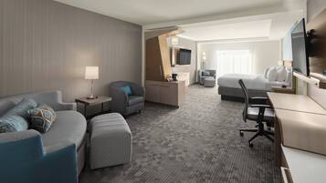 A hotel room with a sofa, armchair, desk, and a bed.
