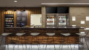 A bar area with a wooden bar counter, metal wire chairs, a beverage cooler, and a menu board.