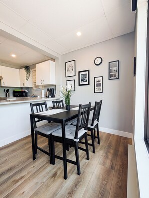 A modern kitchen with white cabinets, a microwave, and a coffee machine. - Hébergement Harvey (Alma)
