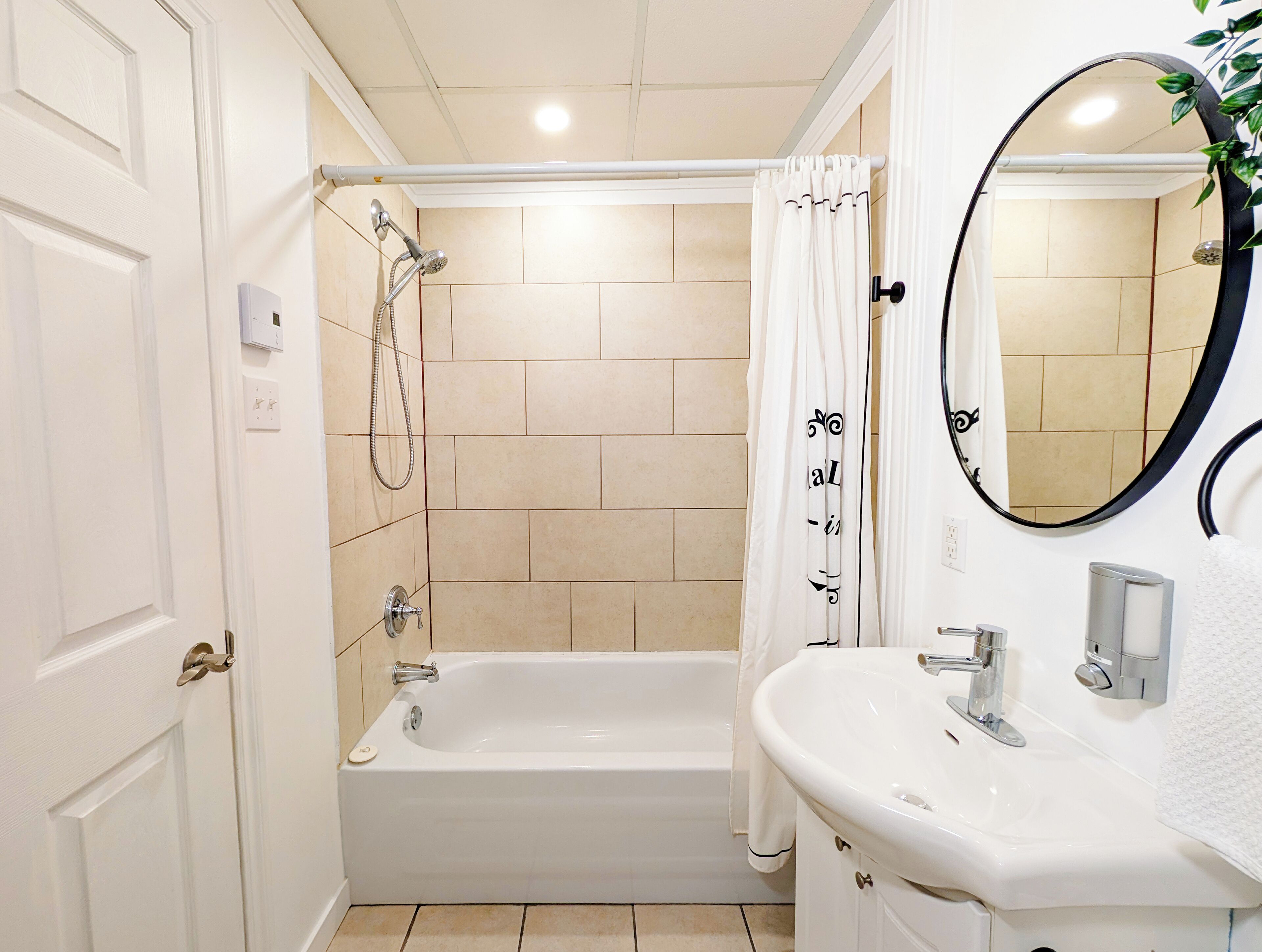 A bathroom with a bathtub, a sink, a mirror, and a shower.