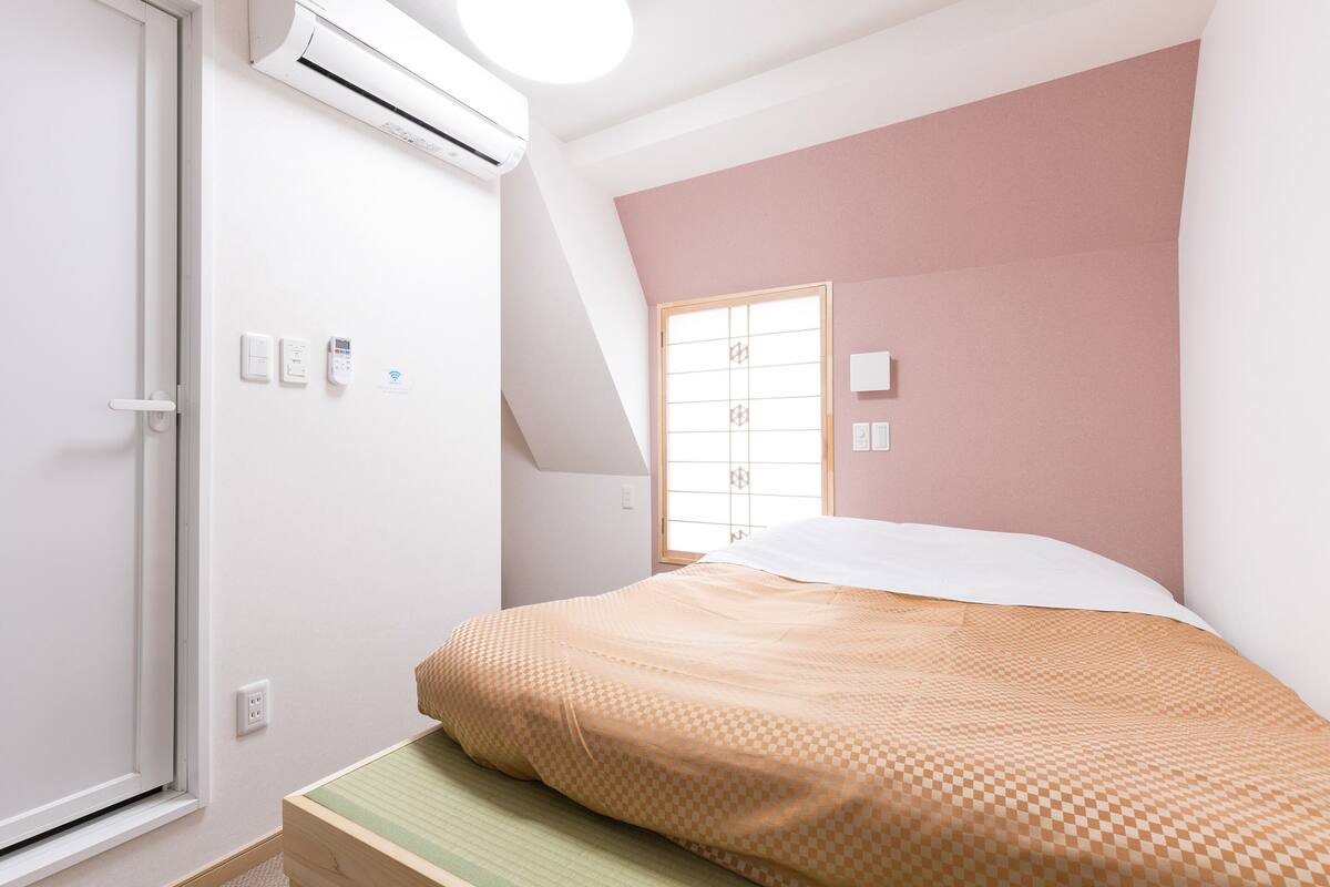 Un dormitorio con cama, ventana y equipo de aire acondicionado.