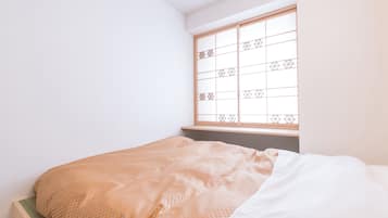 Una camera da letto con un letto, una finestra con motivo geometrico e una parete semplice.