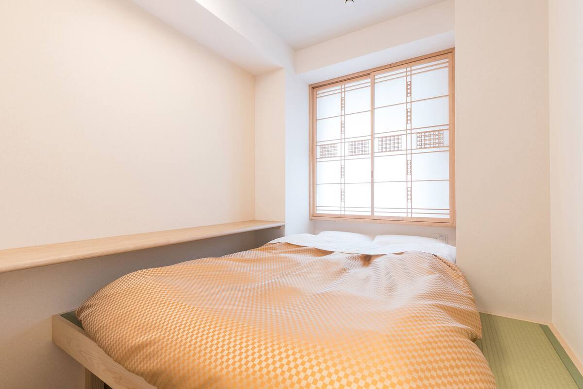 Un dormitorio con cama, ventana de diseño celosía y cabecero de madera.