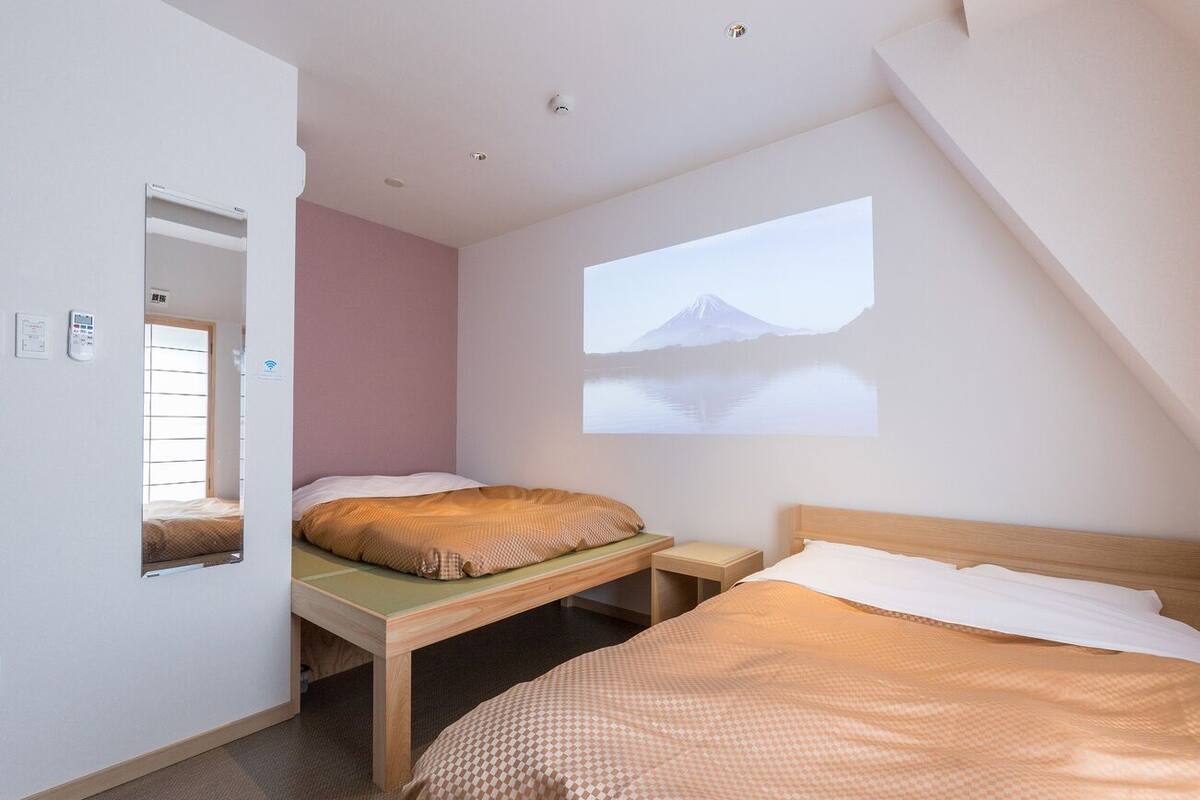 Un dormitorio con dos camas, una ventana y una proyección de una montaña.