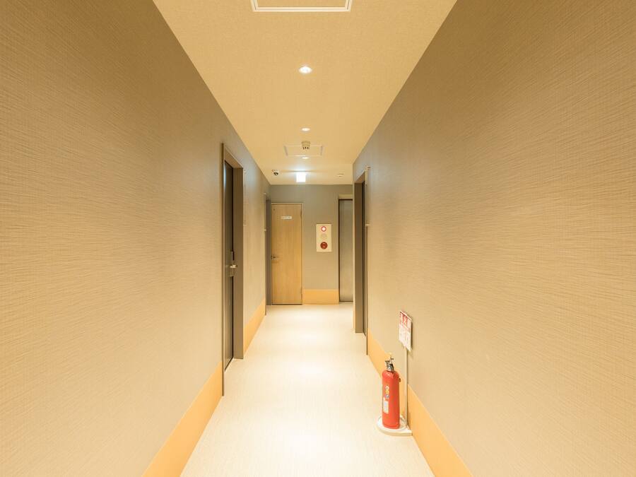Un pasillo con un extintor y una puerta al final.