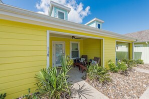 A yellow house with a covered porch, a door marked '18', and a small garden with plants. - Pirates Bay, boat parking, poolfront, pets OK (Port Aransas)