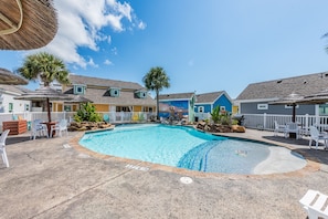A swimming pool with a 'No Diving' sign, surrounded by colorful houses, white fences, and outdoor seating.
