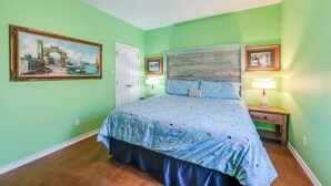 A bedroom with a bed, two bedside tables, a ceiling fan, and a door.