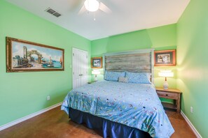 A bedroom with a bed, a nightstand, a lamp, and a door.