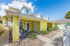 A yellow house with a porch, a small attached garage, and a clear blue sky.