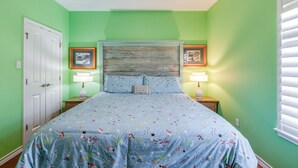 Une chambre à coucher comprenant un lit, deux tables de chevet, une tête de lit et deux tableaux encadrés accrochés au mur.