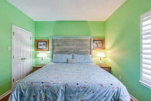 Une chambre à coucher comprenant un lit, deux tables de chevet, une tête de lit et deux tableaux encadrés accrochés au mur.