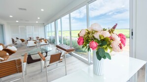 Een moderne hotelkamer met een groot raam, een witte tafel en een bloemenvaas.