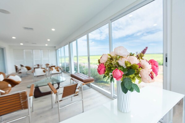 A modern hotel room with a large window, a white table, and a vase of flowers.