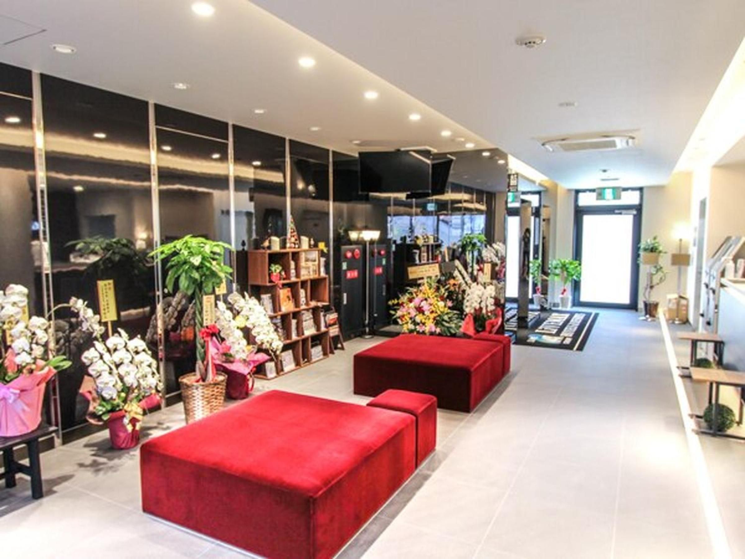 A modern hotel lobby with red seating, a reception desk, and a large window displaying a cityscape.