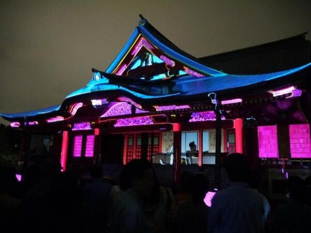 A traditional building with a sloped roof and illuminated by purple and blue lights.