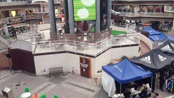 Un centro comercial interior con varios niveles, un atrio central y zonas de estar al aire libre.